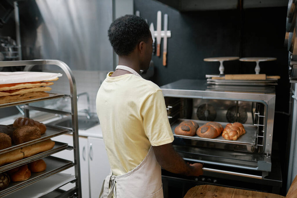 Bäcker backt geflochtenes Brot mit Mohn für den Laden - Foto, Bild