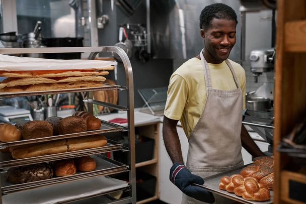 Hombre sonriente disfrutando trabajando en panadería - Foto, Imagen