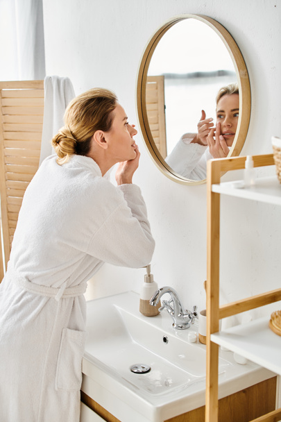attraente donna in bianco comodo accappatoio indossa le lenti a contatto vicino specchio in bagno - Foto, immagini
