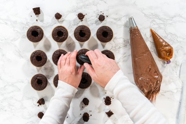 Plat gelegd. Elke chocolade cupcake krijgt een royale vulling van heerlijke karamel, het toevoegen van een extra laag van smaak en verwennerij. - Foto, afbeelding
