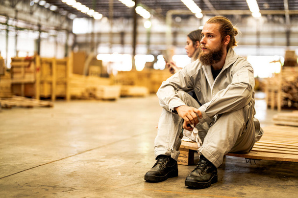 muž dělníci inženýrství sedí s důvěrou v pracovní suite šaty a ruční rukavice v přední stroj. Koncept inteligentního pracovníka v průmyslu. Továrna na dřevo vyrábí dřevěné patro. - Fotografie, Obrázek