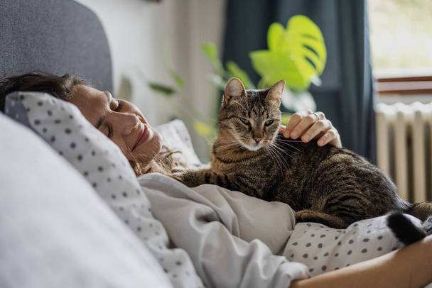 Portrait young beautiful caucasian woman wakes up in the morning. Woman hugging her cat at the morning. Lifestyle with home animals. - Fotografie, Obrázek