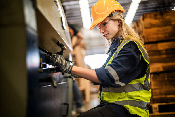 Factory engineer woman standing confidence to control panel switch. Worker works at heavy machine at industry factory. with machinery equipment plant technology. smart industry worker operating. - Photo, Image