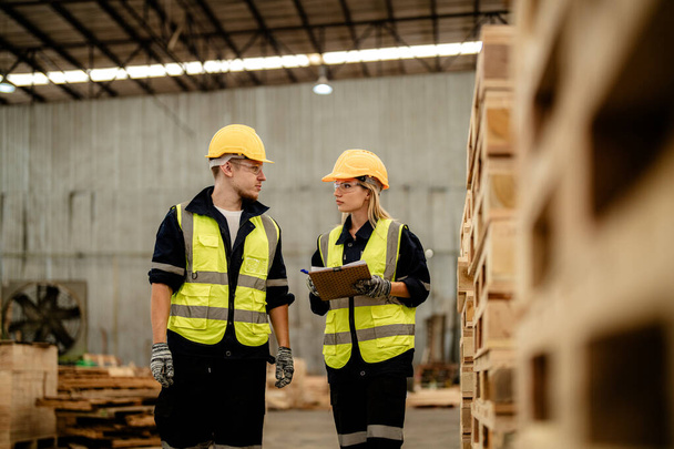 workers man and woman engineering walking and inspecting timbers wood in warehouse. Concept of smart industry worker operating. Wood factories produce wood palate. - Photo, Image