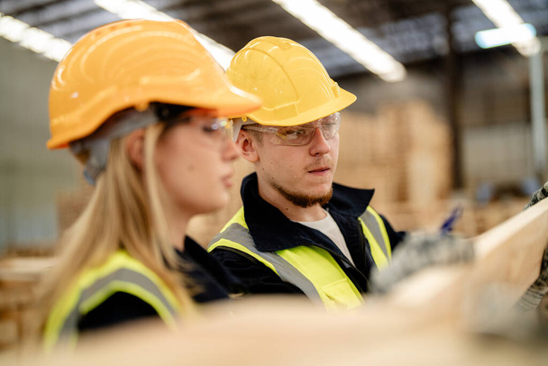 workers man and woman engineering walking and inspecting timbers wood in warehouse. Concept of smart industry worker operating. Wood factories produce wood palate. - Photo, Image