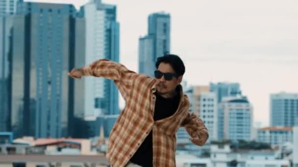 Ισπανόφωνος χορευτής break dancer πρακτική B-boy βήματα στην οροφή με την αστική θέα της πόλης ή ουρανό scrapper. Νεανικό μοντέρνο χορευτικό συγκρότημα που κάνει χιπ χοπ. Στυλ, μόδα, δράση. Υπαίθριο άθλημα 2024. hiphop. - Πλάνα, βίντεο