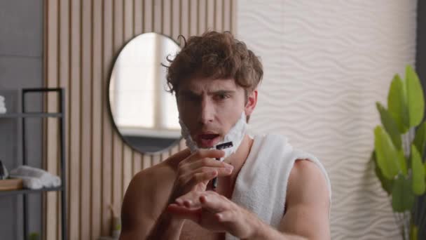Kaukázusi Y-generációs srác férfi vicces gondtalan humoros humoros férfi habos szakállal borotválkozás zselé hab az arc éneklés dal borotválkozás borotva énekel tánc szórakozás ápolás eljárás reggeli rutin - Felvétel, videó