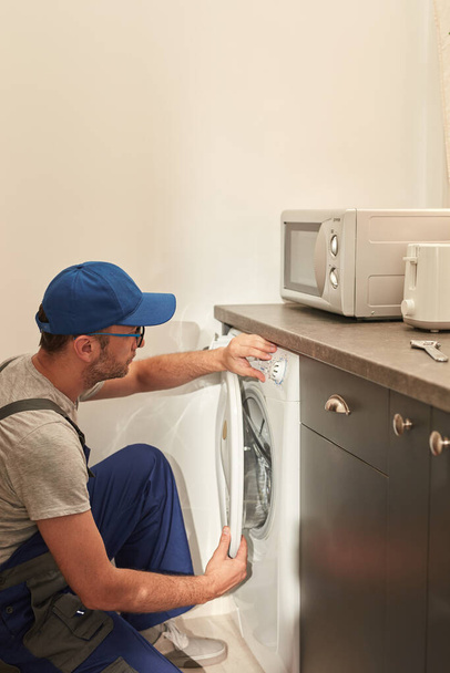 Handyman arreglando la lavadora rota en el apartamento. - Foto, imagen