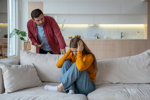 Offended woman closed ears sitting on home couch while man scream talk in family quarrel scandal. Upset wife and husband have misunderstanding, toxic relationships. Marital discord, emotional violence - Photo, Image