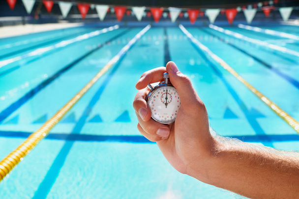 Hand, stopwatch and swimming pool for sport, training and workout with preparation for competition. Person, coach or mentor with clock, timer or watch for speed, progress and tracking lap for race. - Photo, Image