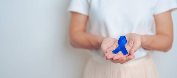 Marzo mes de conciencia del cáncer colorrectal, médico con cinta azul oscura para apoyar a las personas que viven y enferman. Salud, esperanza y concepto del Día Mundial del Cáncer - Foto, Imagen