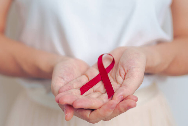 woman with Burgundy Red Ribbon for March multiple myeloma Cancer and December World Aids Day Awareness month. Healthcare and world cancer day concept - Photo, Image