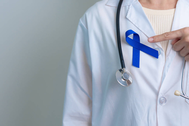 Μάρτιος Colorectal Cancer Awareness μήνα, γιατρός με σκούρα μπλε κορδέλα για την υποστήριξη των ανθρώπων που ζουν και ασθένεια. Υγεία, ελπίδα και έννοια Παγκόσμια Ημέρα κατά του Καρκίνου - Φωτογραφία, εικόνα