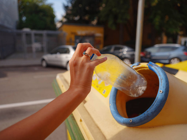 donna gettando bottiglia di plastica Riciclaggio bin stand sulla strada europea. Rifiuti raccolta rifiuti prima di cadere nel cestino della spazzatura per salvare il mondo, la cura dell'ambiente. Concetto di gestione del riciclaggio dei rifiuti inquinanti - Foto, immagini