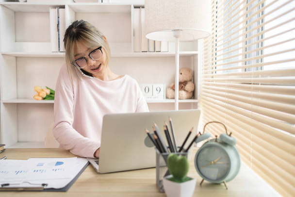 Junge Frau Multitasking: Tippen am Laptop und Telefonieren im Home Office, Home Workspace, Junge Frau, die viel Arbeit hat und sehr beschäftigt ist. - Foto, Bild