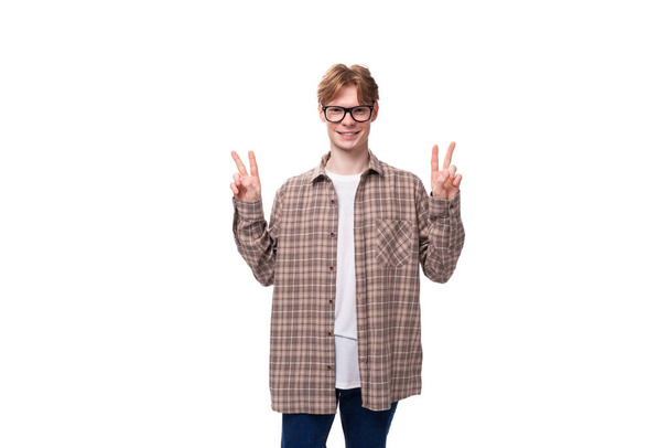 een jonge vriendelijke Europese man met rood kort haar en een bril draagt een geruit shirt. - Foto, afbeelding