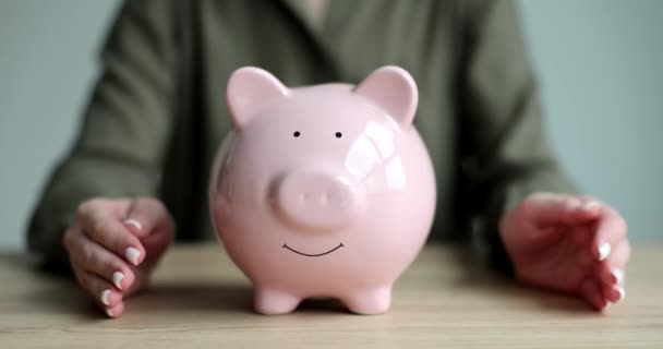 Woman hands hugging pink piggy bank with coins closeup 4k movie slow motion. Saving finance concept - Footage, Video