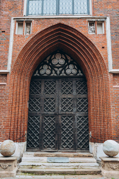 Puerta de entrada de madera decorativa antigua a la iglesia. Grandes puertas arqueadas de madera con detalles tallados, elementos metálicos decorativos - Foto, imagen