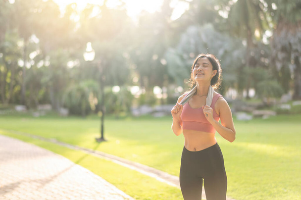Fit happy smile 30s young Asian woman in sportswear enjoys refreshing sunset run in nature. The silhouette of figure against the setting sun is beautiful sight. Fitness, health, or motivation concept. - Photo, Image
