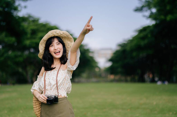 Retrato de mujer joven asiática viajero con sombrero de tejer y cesta y una cámara en verde parque público fondo de la naturaleza. Viaje viaje estilo de vida, viajero mundial o concepto de turismo de verano de Asia. - Foto, Imagen
