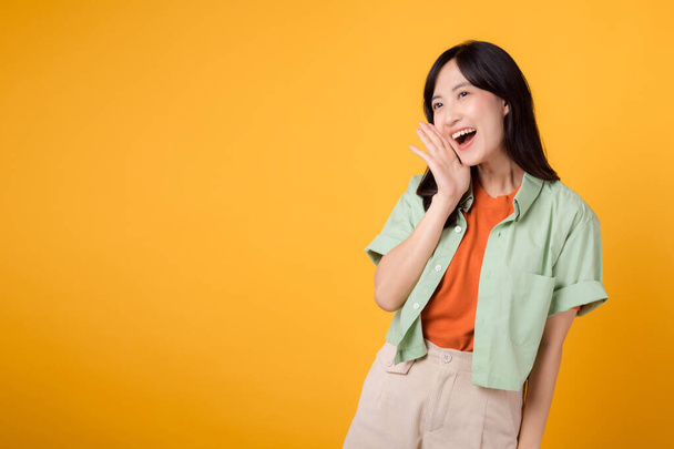 Asiatische Geschäftsfrau in ihren Dreißigern im Gespräch in einem Studio. Rufen, lächeln und gestikulieren mit der Hand isoliert auf gelbem Hintergrund. Wirtschaft, Kommunikation und Frauen im Arbeitsmarktkonzept. - Foto, Bild