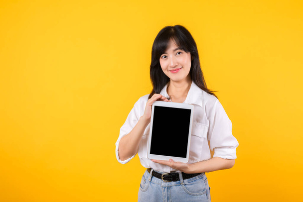 Fiduciosa donna asiatica abbraccia l'era digitale, tenendo tablet su uno sfondo giallo vibrante. connettività moderna, tecnologia-savviness e potenziamento. stili di vita digitali e progressi tecnologici. - Foto, immagini