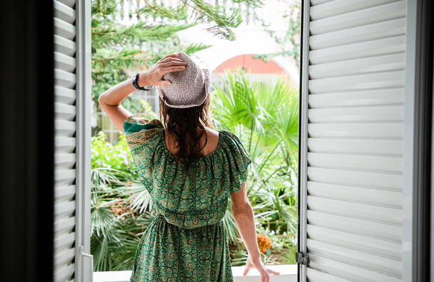 жінка насолоджується пишною зеленню перед готельною кімнатою - Фото, зображення