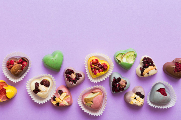 chocolate sweets in the form of a heart with fruits and nuts on a colored background. top view with space for text, holiday concept. - Fotoğraf, Görsel