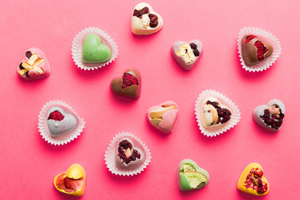 chocolate sweets in the form of a heart with fruits and nuts on a colored background. top view with space for text, holiday concept. - Foto, afbeelding