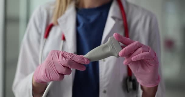 A női orvos munkaruhában ultrahangos jelátalakítót tart. Professzionális berendezés az emberi test megzavarásának kimutatására a lassú mozgású klinikán - Felvétel, videó
