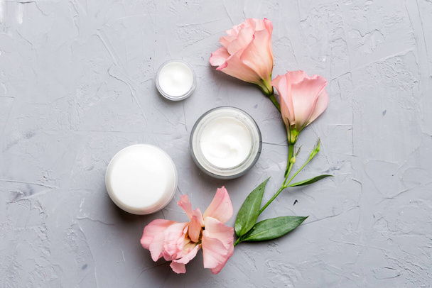 Composition with cosmetic products and beautiful roses on cement background. Flat lay. - Photo, Image