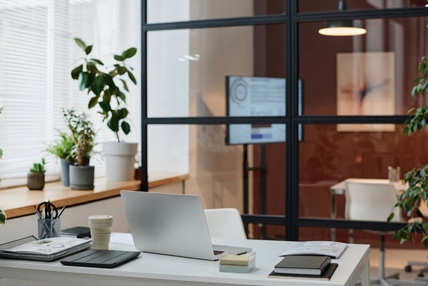 Современный интерьер городского офиса с аккуратным белым столом напротив стеклянной стены конференц-зала - Фото, изображение