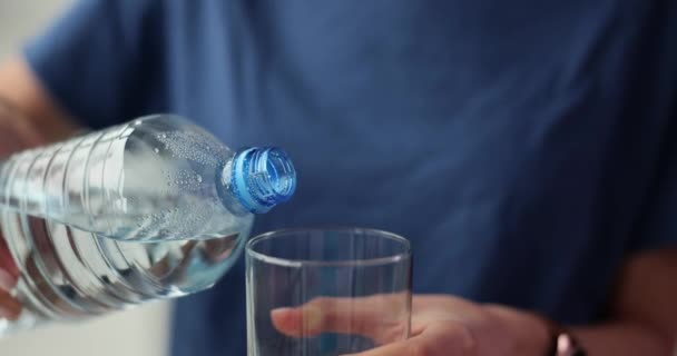La hembra vierte agua limpia en vidrio transparente en cámara lenta. Mujer sedienta vierte agua potable pura de la botella en el vidrio va a beber - Imágenes, Vídeo
