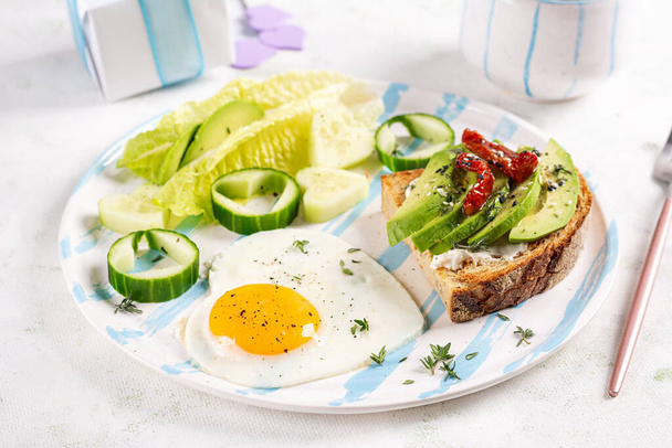 Ρομαντικό πρωινό για του Αγίου Βαλεντίνου. Τηγανητό αυγό και τοστ με αβοκάντο και τυρί κρέμα. - Φωτογραφία, εικόνα