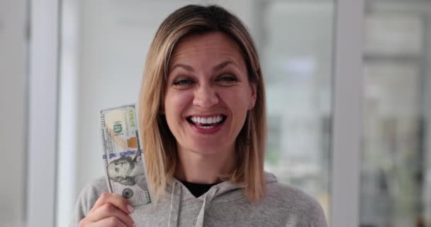 La mujer sostiene billetes de cien dólares gritando alegremente en cámara lenta. Ganador de la lotería expresa alegría y felicidad sosteniendo cien dólares con sonrisa - Metraje, vídeo