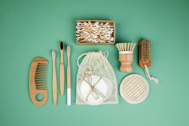 Stel eco-vriendelijke bad apparaten. Washandjes, bamboe tandenborstels en gezichtspons, kam en oorstokjes op een groene achtergrond. Vlakke plaat - Foto, afbeelding
