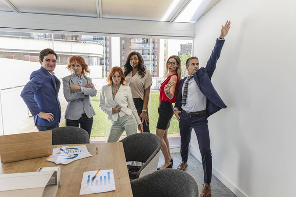 группа представителей разных поколений и разных рас бизнеса, в офисе, в шутливой позе - Фото, изображение