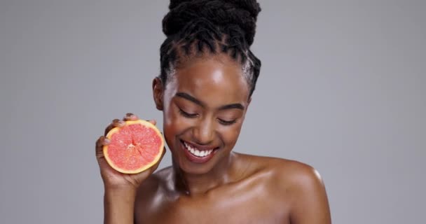Grépfrút, boldog szépség és arc a nő a stúdióban a C-vitamin ellátások, méregtelenítés vagy izzás szürke háttér. Portré, afrikai modell vagy citrusfélék a fenntartható bőrápoláshoz, öko kozmetikumokhoz vagy étrendhez. - Felvétel, videó