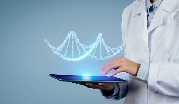 L'expertise rencontre la technologie : plan rapproché du médecin exerce CRISPR et réalité augmentée pour décoder les secrets de l'ADN virtuel pour les patients sur tablette numérique, fond bleu studio, espace libre - Photo, image