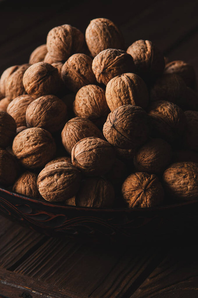 Raskas koko saksanpähkinät kuori kulhoon ruskea puinen pöytä. Pystykuva - Valokuva, kuva