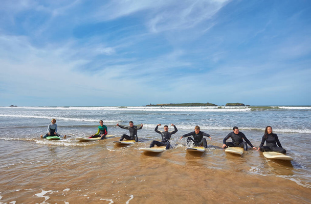 Skupina mladých živých surfařů zachycuje kolektivní okamžik s prkny na břehu oceánu v marocké Essaouiře. Kamarádství surfařské kultury na pozadí malebného pobřežního šarmu Essaouiry - Fotografie, Obrázek