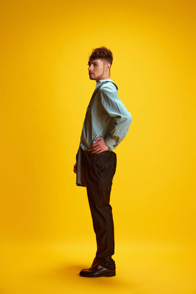 Side view full-length portrait of young man with female and male appearance dressed in smart casual outfit showing self-expression and confidence. Concept of self-expression, beauty, lifestyle. Ad - Photo, Image