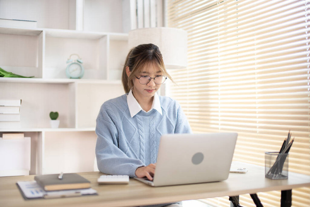 Egy nő gépel egy laptop előtt, kézzel nyomja meg a laptop billentyűzetét, szándékában áll dolgozni az irodában. - Fotó, kép
