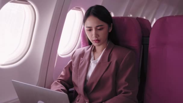 Une femme d'affaires asiatique travaille sur son ordinateur portable, enregistrant et analysant activement les tâches pendant son vol. Elle se consacre à maximiser la productivité pendant le transport.  - Séquence, vidéo
