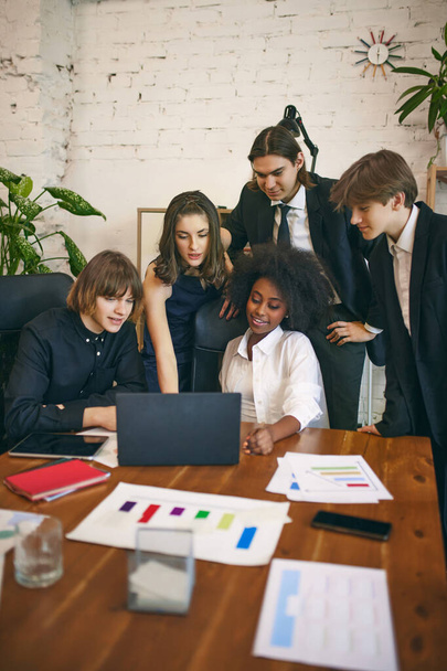 Motivált és fókuszált üzletemberek csoportja, akik laptopot használnak, miközben együtt dolgoznak a modern munkahelyen. Üzleti koncepció, csapatmunka, iroda, vállalati tréningek, munka, munkahely, karrierfejlesztés. - Fotó, kép