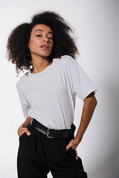 ελκυστική Αφροαμερικανή που ποζάρει με τα χέρια στις τσέπες και κοιτάζει την κάμερα, την έννοια της μόδας - Φωτογραφία, εικόνα