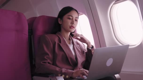 Una donna d'affari asiatica sta lavorando sul suo computer portatile, registrando e analizzando attivamente le attività durante il suo volo. Si dedica a massimizzare la produttività mentre è in transito.  - Filmati, video