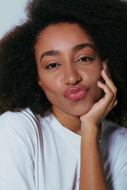 Porträt einer fröhlichen hübschen afrikanisch-amerikanischen Frau, die mit gestampften Lippen in die Kamera blickt, Modekonzept - Foto, Bild