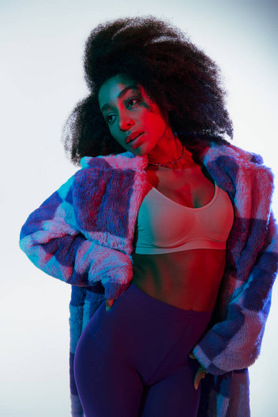 sexy chic african american woman in vibrant faux fur and bra looking away in red and blue lights - Foto, imagen