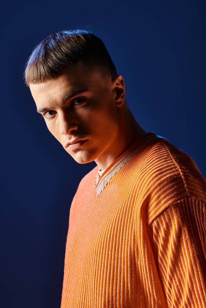 Portré fiatal stílusos férfi narancssárga ing nézi kamera sötét kék háttér - Fotó, kép